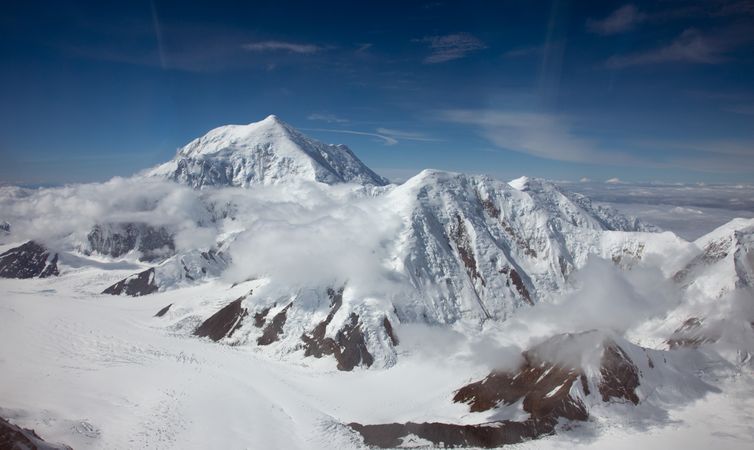 Snow covered mountain peaks with wispy clouds in Denali, Alaska