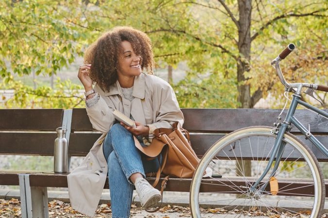 Smiling Black woman with bicycle in park