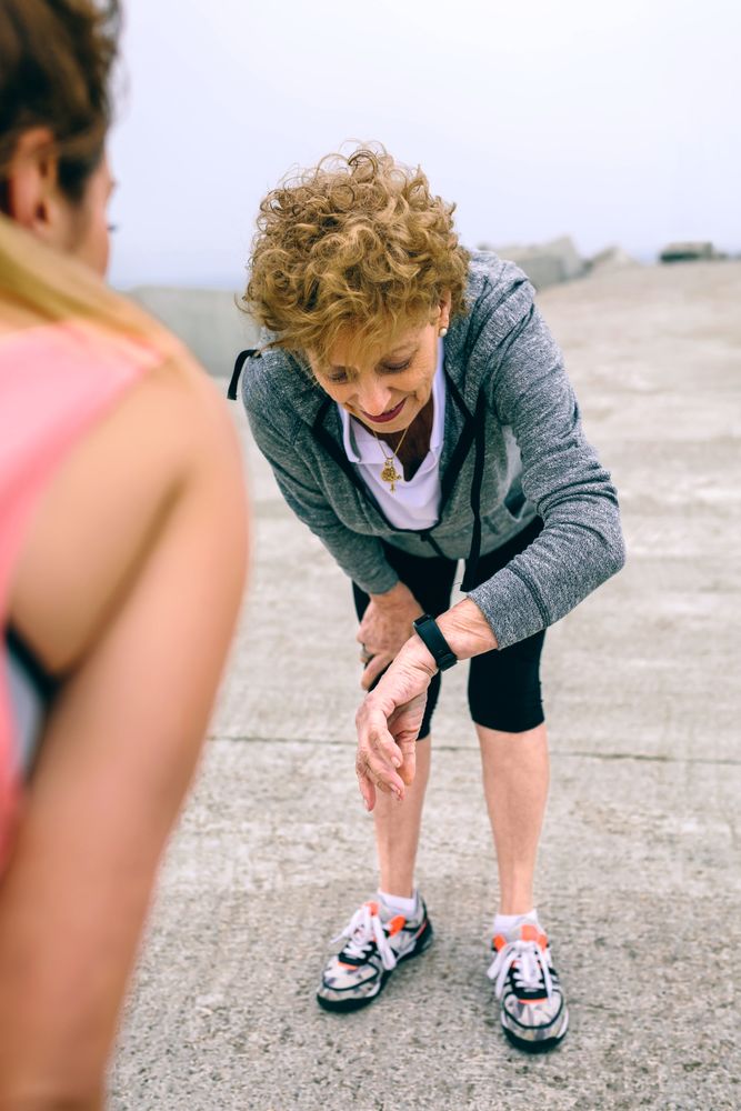Mature woman looking smart watch with female coach