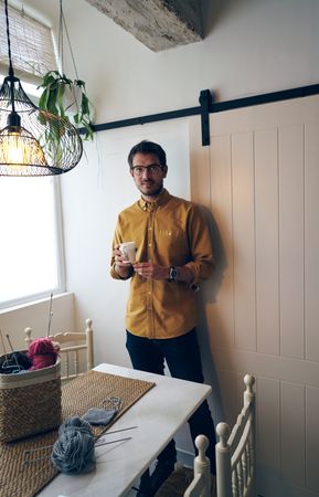 Man drinking hot tea during knitting