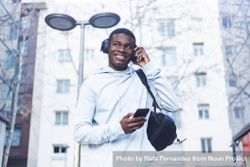 Young Black man walking in the street while listening music on headphones 0v3GAR