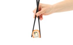 Female hand with chopsticks holds sushi roll, isolated on plain background