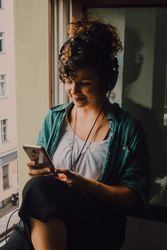 Cheerful woman in headphones using smartphone at home