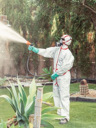 Fumigator in uniform spraying substance on garden