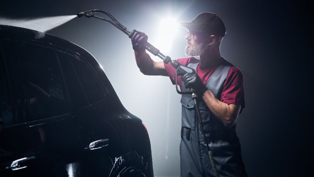 Advertising Style Photo of a Professional Car Wash Specialist Using a High Pressure Washer to Clean and Prepare a High Tech Family Electric SUV for Detailing