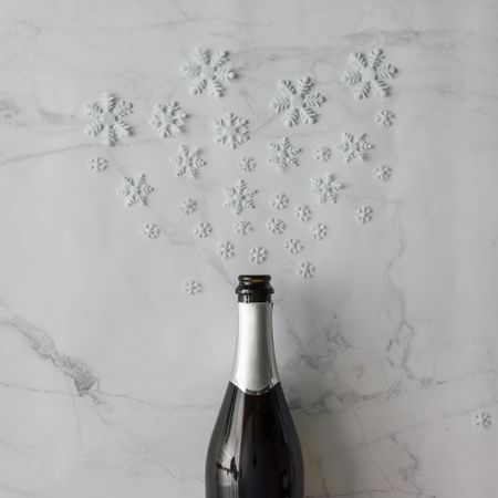 Champagne bottle with snow flakes on marble background