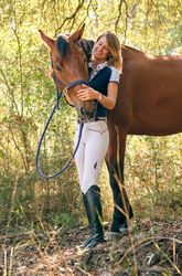 Smiling woman embracing horse in forest