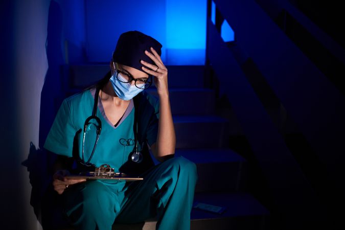 Pensive female doctor sitting on stairs