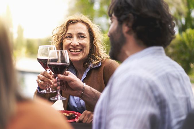Happy couple having fun toasting outdoors sitting at the barbecue table