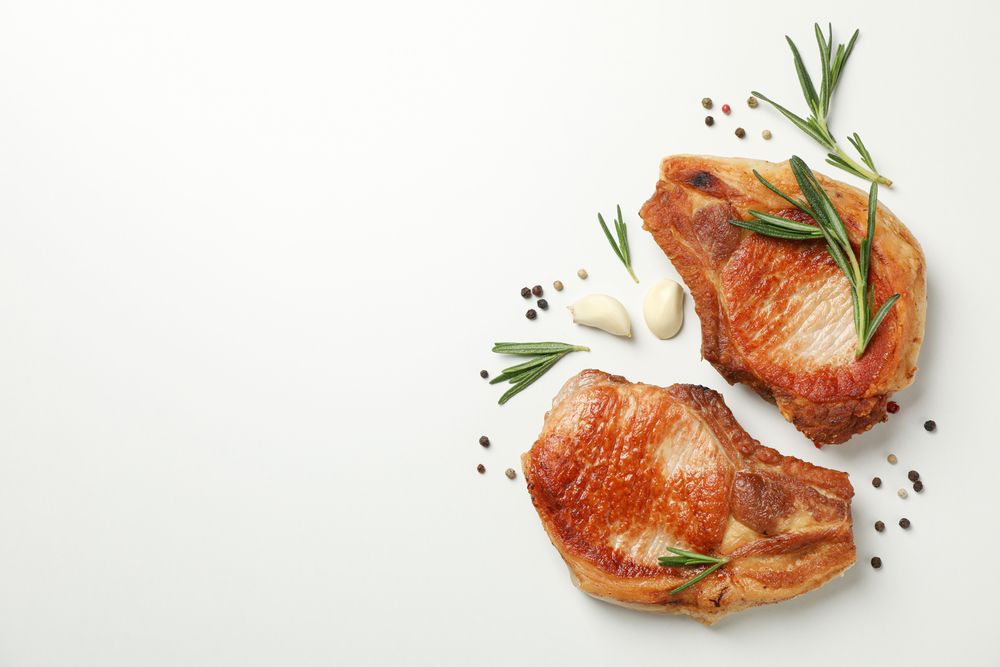 Fried steaks with spices on blank background, top view