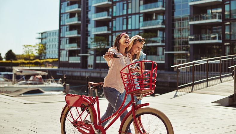 Two close female friends happily walking along the waterfront