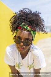 Serious Black woman looking up over sunglasses against yellow wall 0v3MeR