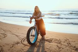 Joyful woman riding bicycle along peaceful beach
