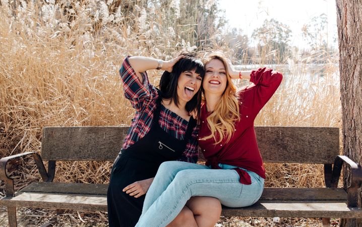 Young women sitting on bench and looking at camera