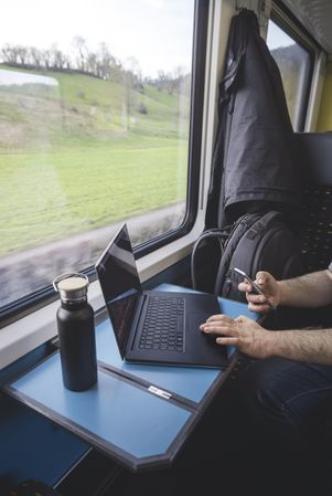 Man using laptop and phone inside train