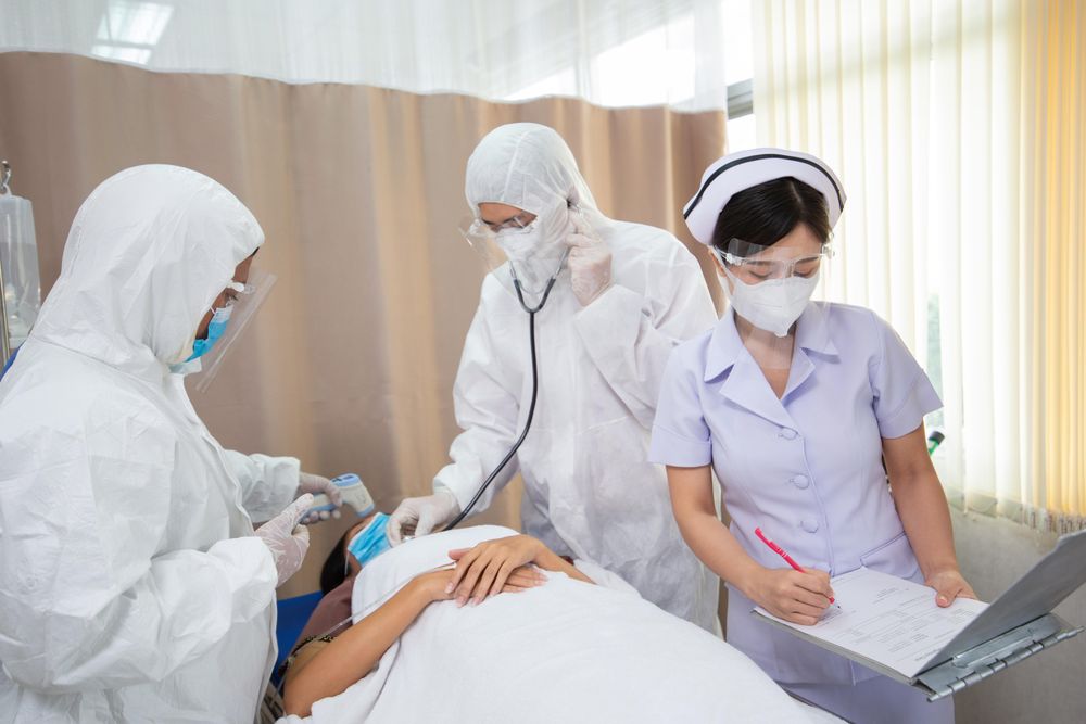 Patient lying in hospital bed surrounded by doctors and nurse