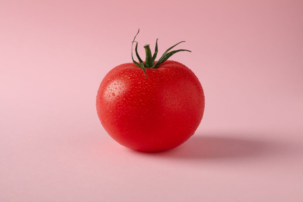 Fresh ripe tomato on pink background, close up