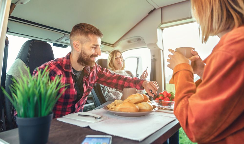 Friends enjoying coffee and pastries in back of camper
