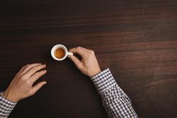Arms in plaid shirt with single espresso shot