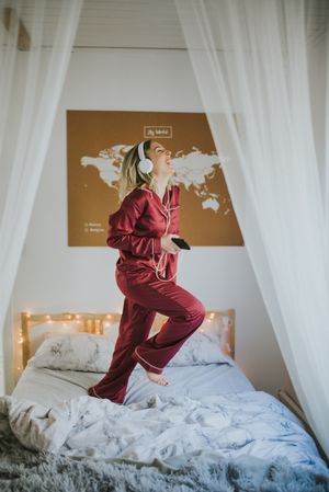 Woman with headphones dancing in bed