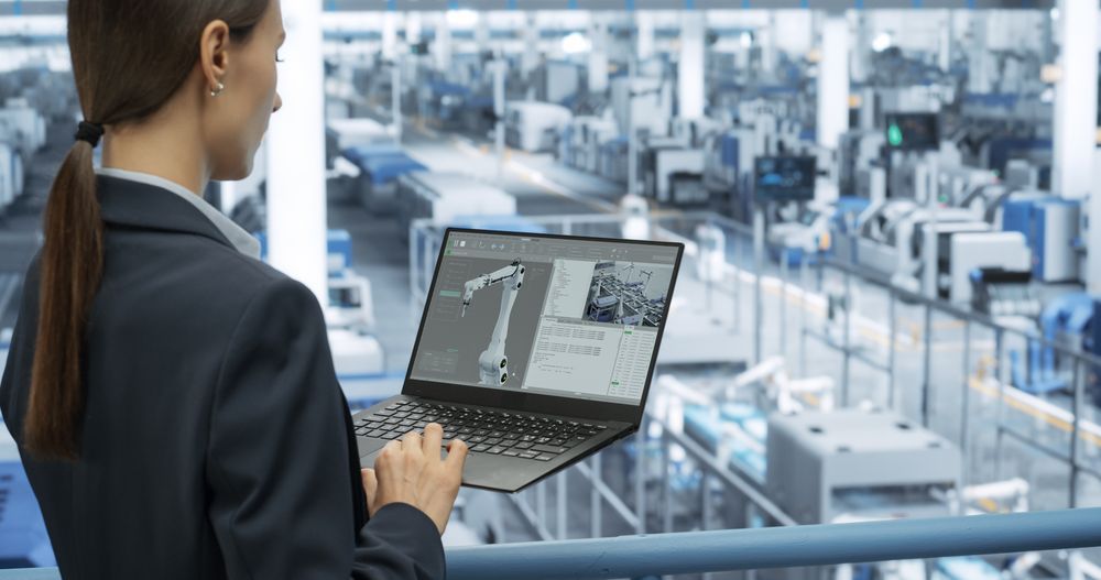 Electronics Manufacturing Technician Working on a Laptop Computer at a Factory Space. Female Specialist Developing, Maintaining, Upgrading Programs for Machine Production and Assembly