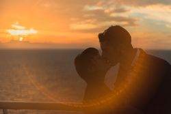Young people kissing in sunset light on ship
