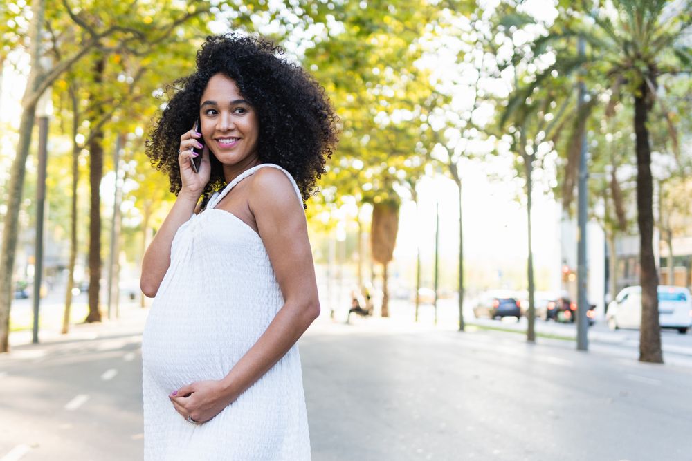 Smiling Black pregnant woman talking on smartphone