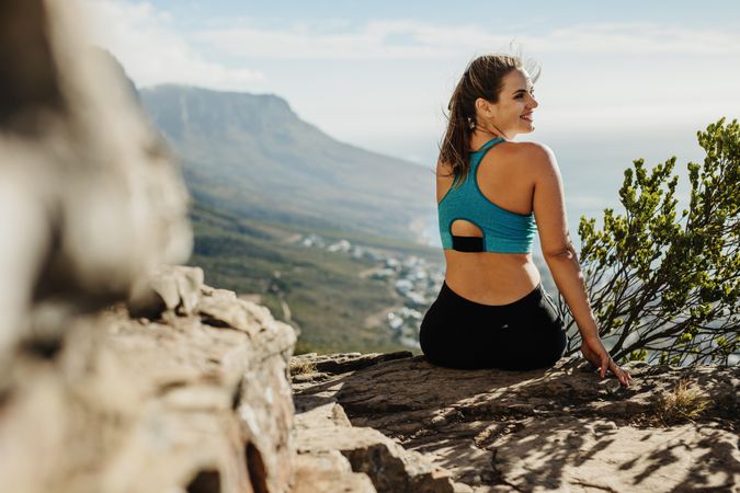 Rear view of a healthy woman sitting on a cliff