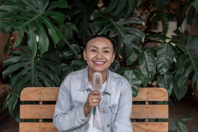 A young Hispanic woman is smiling while eating an ice cream