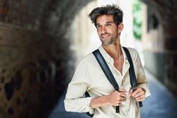 Handsome man standing within arch of city street