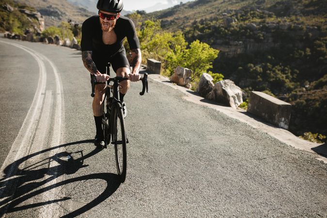 Bicyclist struggling to bike up steep hill outdoors
