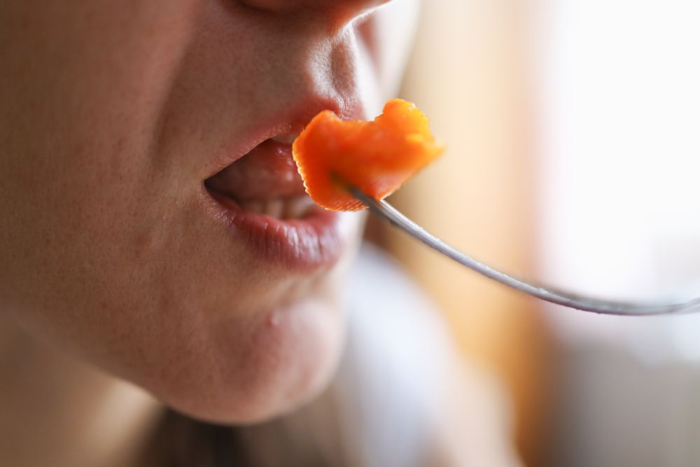 Nourishing Bite: Woman Eating Carrot as a Vitamin-Packed Nutritious Snack.