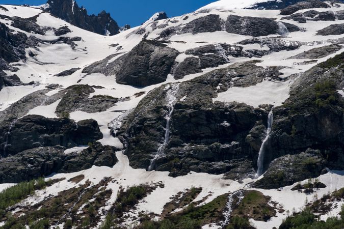 Snow-covered rocky mountain slopes with multiple waterfalls