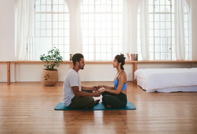 Side view of beautiful young couple doing yoga at home