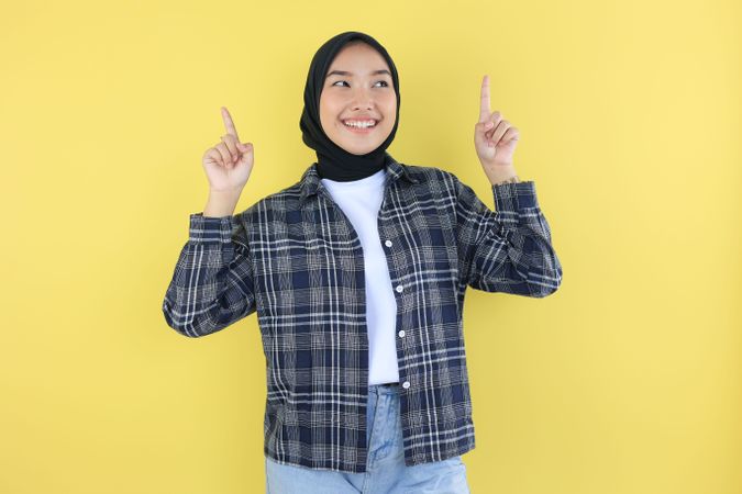 Happy Excited Asian Girl with Hijab Pointing Two Finger Up at Copy Space