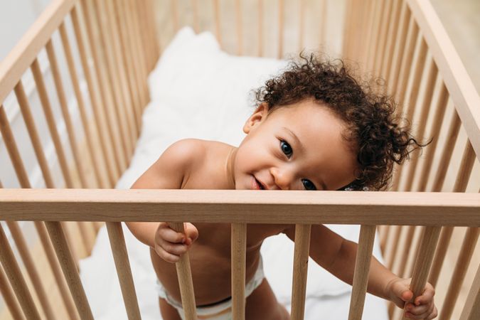 Cute baby boy standing up and leaning in his crib