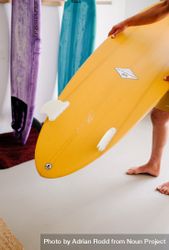Man choosing surfboard at home before heading to the beach 0V9wXb