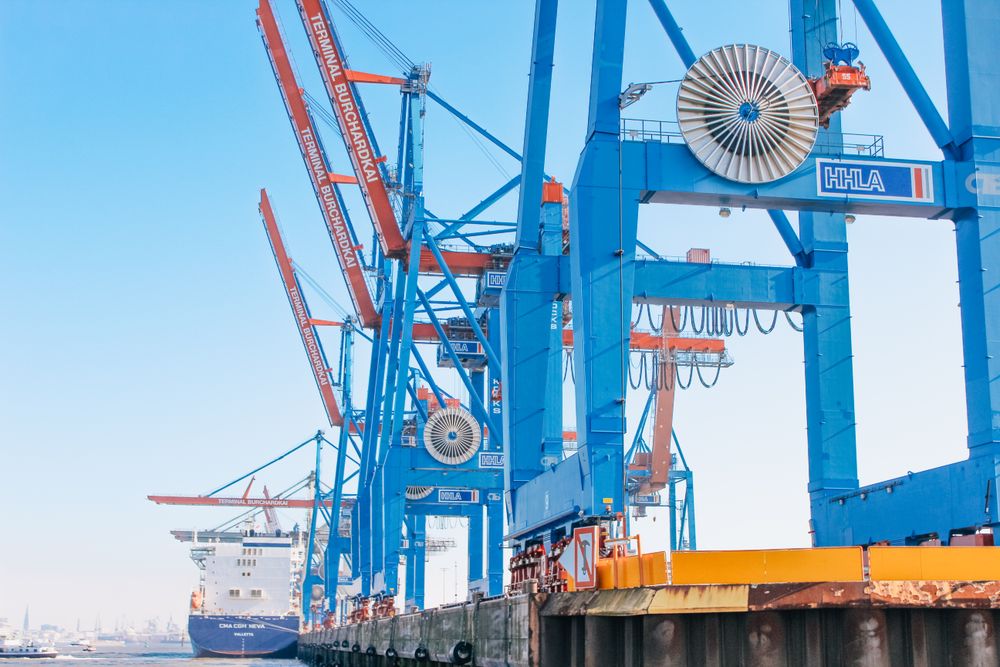 Ship docked beside blue cranes at seaport