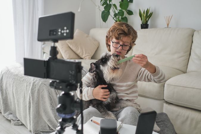 Preteen blogger recording video with dog at home