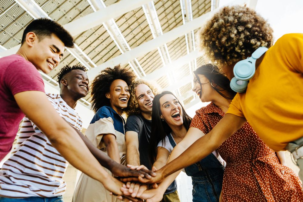 Multiracial happy friends with hands in stack