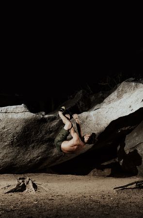 Man practicing rock climbing among large rocks in a forest
