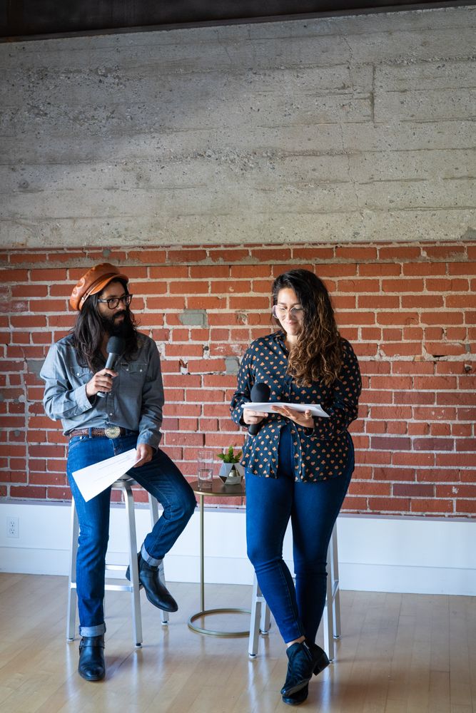 Two people perched on chairs giving a talk
