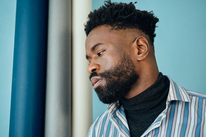 Closeup profile of Black bearded man in striped blue shirt