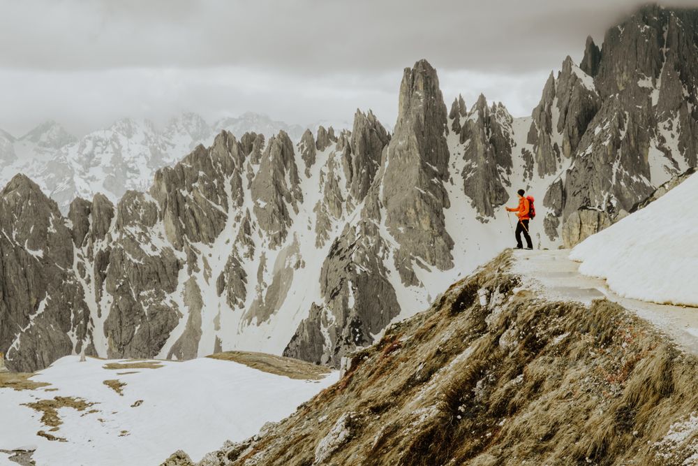 Man on hill near snow covered mountains