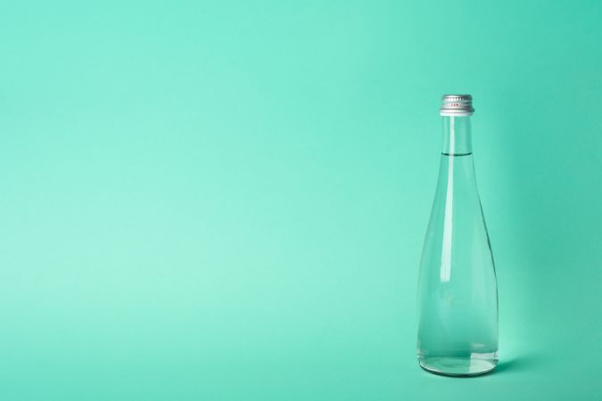 Full glass water bottle in green room, copy space