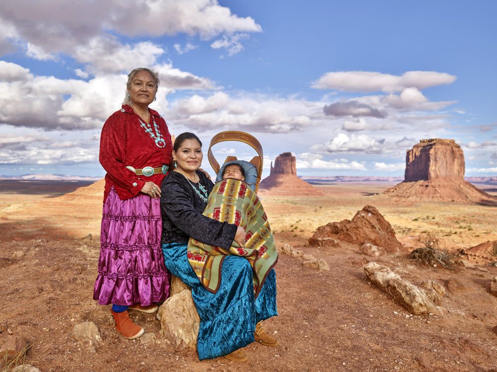 Three generations of Navajo family members posing in Monument Valley, AZ
