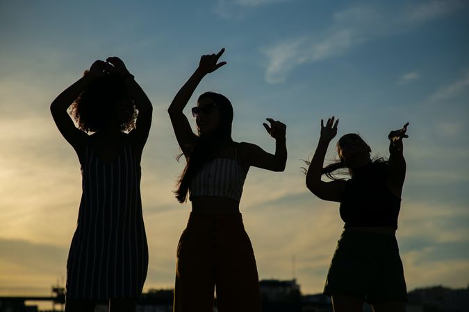 Silhouette of three women standing outdoor at sunset