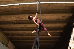 Slim woman doing yoga with aerial silks in city