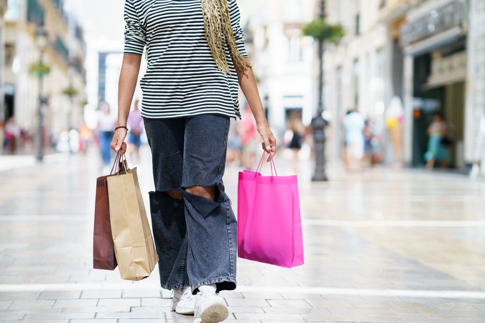 Cropped shot of female legs walking in shopping area with her purchases