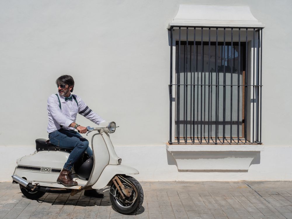 Trendy man sitting on vintage scooter